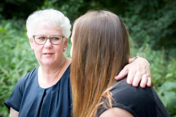 Oudere vrouw slaat arm om jongere vrouw